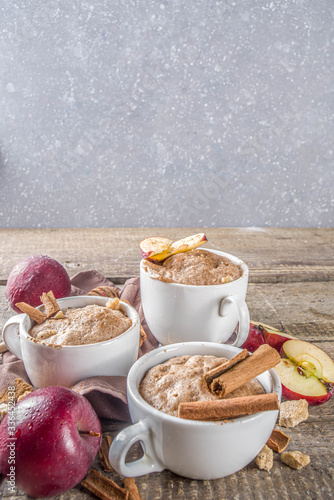 Quick autumn dessert idea. Autumn apple pie mugcake with red apples, cinnamon, spices, Rustic wooden background copy space photo