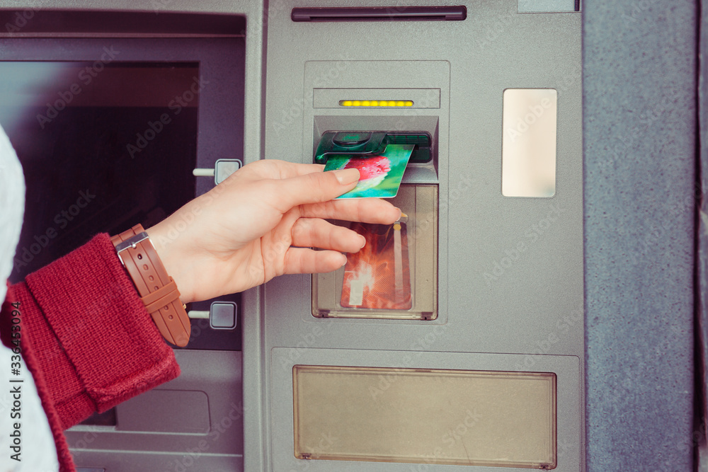 Hand of woman uses credit card to withdraw at Atm Bank terminal. Modern style. ATM cash terminal with display Hand of woman uses credit card to withdraw at Atm Bank terminal. Modern style. ATM cash terminal with display