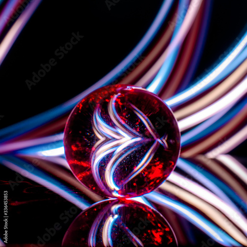 glass ball on a black background with reflection in colored light rays, abstract