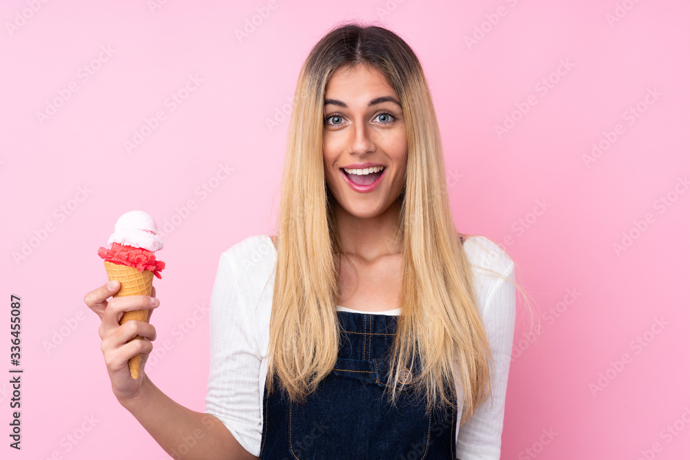 Young Uruguayan woman with a cornet ice cream over isolated pink background with surprise and shocked facial expression