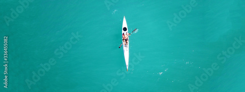 Aerial drone ultra wide top down photo of man paddling in sport canoe in emerald calm water lake