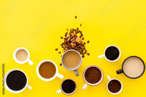 Many cups of coffee on yellow background top view copy space