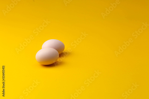 two home-grown organic chicken eggs on a yellow background
