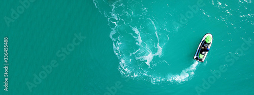 Aerial drone top down ultra wide photo of jet ski watercraft cruising in low speed in tropical exotic lake with calm emerald waters