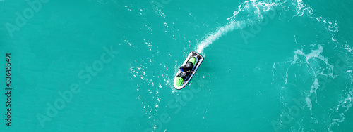 Aerial drone top down ultra wide photo of jet ski watercraft cruising in low speed in tropical exotic lake with calm emerald waters © aerial-drone