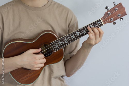 Woman hands playing ukulele on the gray background