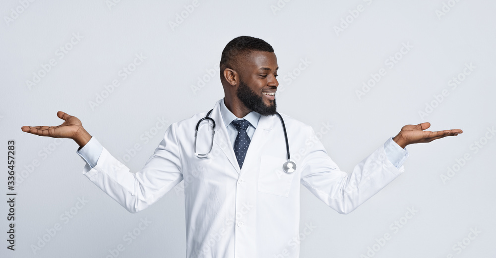 Smiling african doctor holding something invisible on his hands Smiling african doctor holding something invisible on his hands