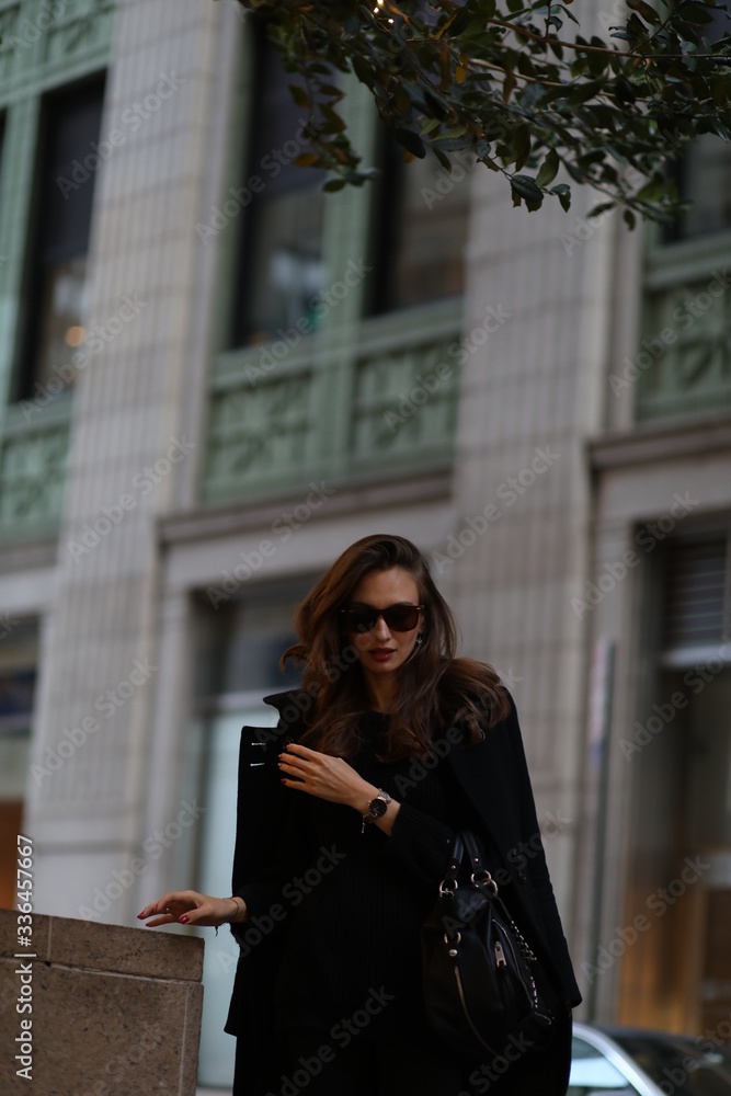 A beautiful woman in a black long coat walks through the streets of New York