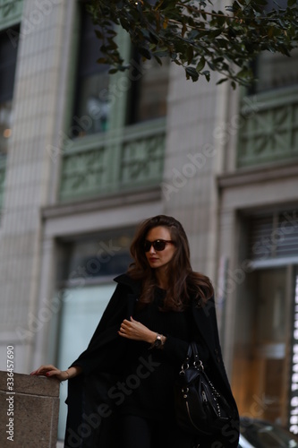 A beautiful woman in a black long coat walks through the streets of New York