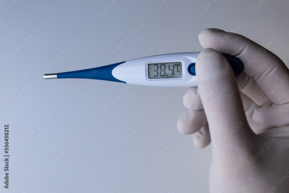 Obraz premium Hand in a medical glove holds a thermometer.