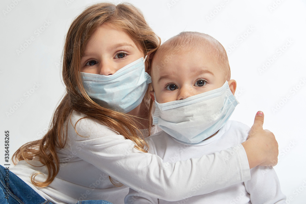 A brother and sister wearing white shirts and face masks on a white background