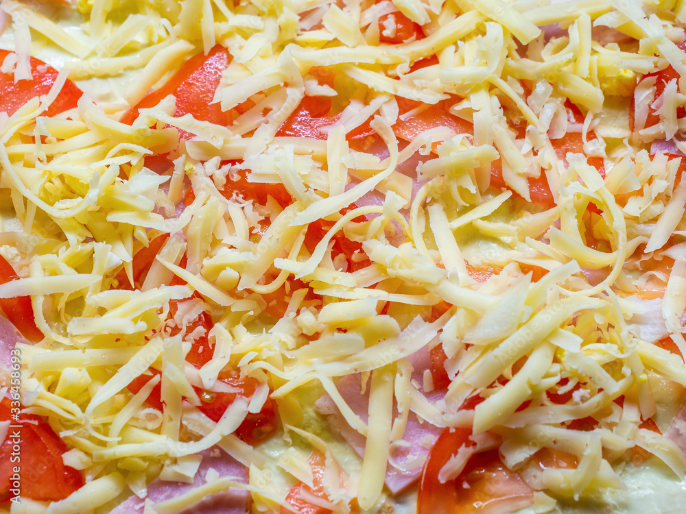 Preparation for baking in the form of tomatoes and ham laid out on the dough and sprinkled with grated cheese Preparation for baking in the form of tomatoes and ham laid out on the dough and sprinkled with grated cheese