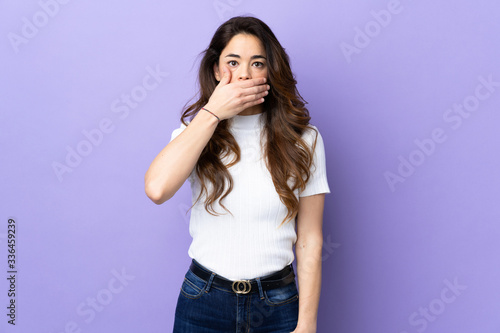 Woman over isolated purple background covering mouth with hand © luismolinero