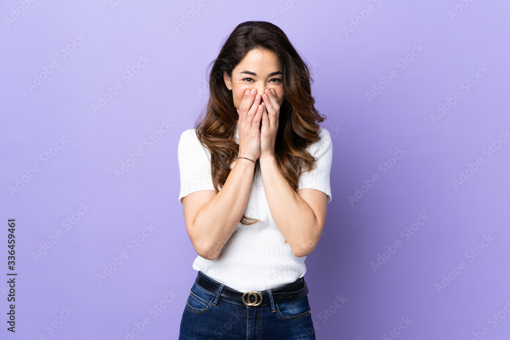 Woman over isolated purple background happy and smiling covering mouth with hands Woman over isolated purple background happy and smiling covering mouth with hands