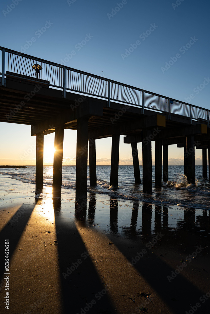Sunrise over Atlantic Ocean, blue sky, piers. Pier and blue Atlantic Ocean. Red sky sun beams. Sunrise over Atlantic Ocean, blue sky, piers. Pier and blue Atlantic Ocean. Red sky sun beams.