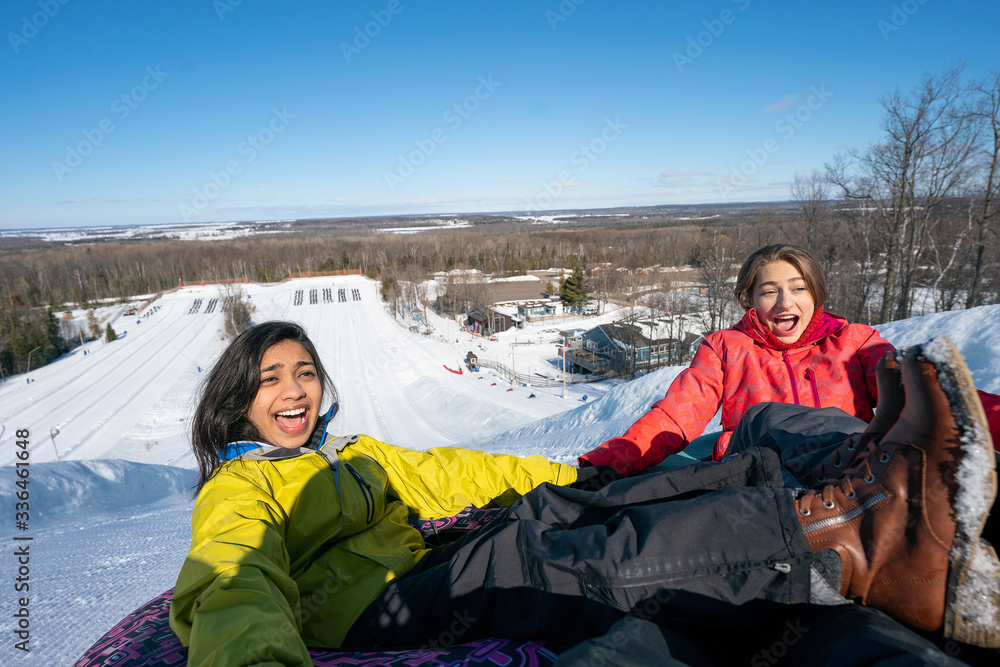 Girlfriends snow tubing in the winter in Canada