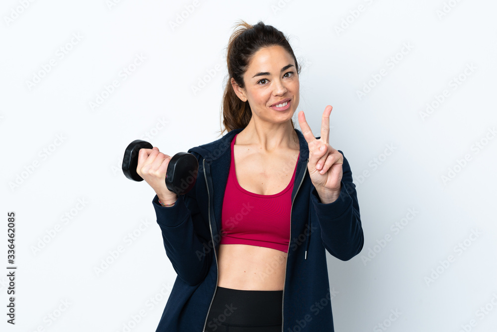Sport woman making weightlifting over isolated white background smiling and showing victory sign Sport woman making weightlifting over isolated white background smiling and showing victory sign