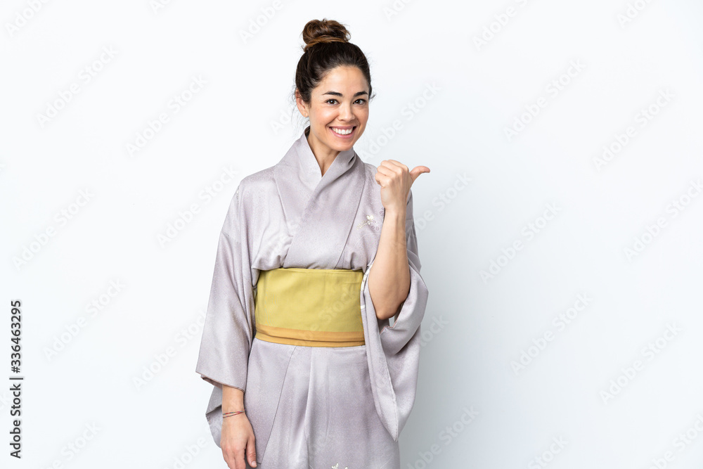 Woman wearing kimono over isolated background pointing to the side to present a product Woman wearing kimono over isolated background pointing to the side to present a product