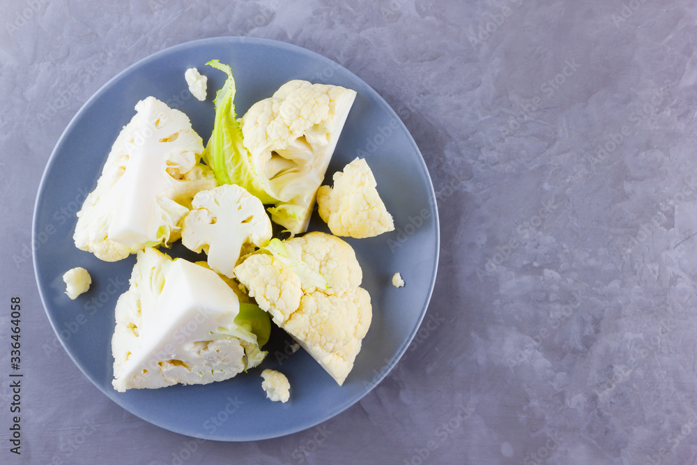 Cauliflower on a gray plate. Sliced fresh cauliflower on a cement background. Slices of organic cabbage on a plate. Top view. Copy space Cauliflower on a gray plate. Sliced fresh cauliflower on a cement background. Slices of organic cabbage on a plate. Top view. Copy space