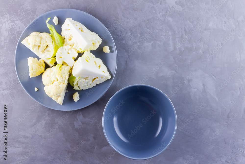 Cauliflower on a gray plate. Sliced fresh cauliflower on a cement background. Slices of organic cabbage on a plate. Top view. Copy space Cauliflower on a gray plate. Sliced fresh cauliflower on a cement background. Slices of organic cabbage on a plate. Top view. Copy space