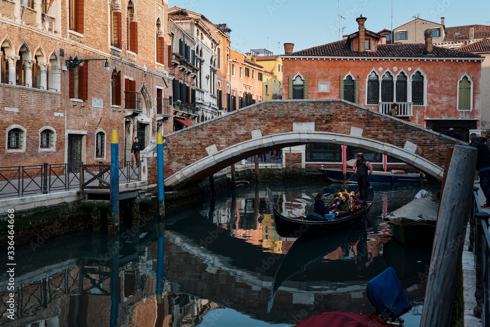 A gondola crossing a small bridge and heart of Venice