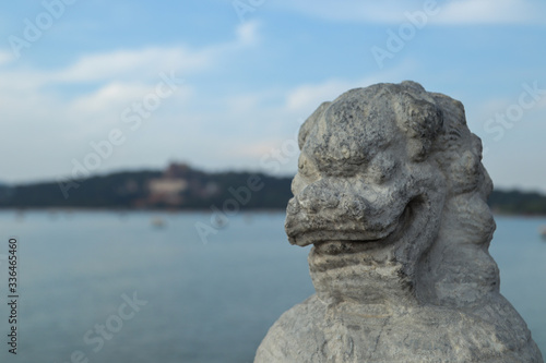 Close up of a dragon's portrait statue with a lake in the background