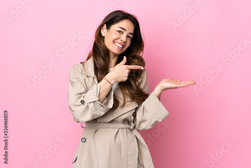 Woman over isolated background holding copyspace imaginary on the palm to insert an ad