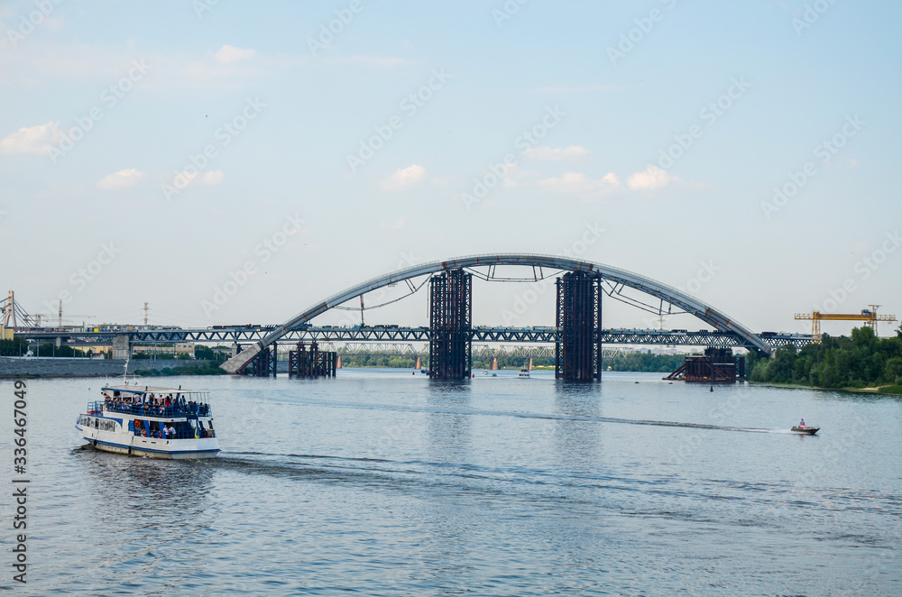 View from river port to tourist boat and The Podilsko-Voskresensky Bridge over the Dnieper River in Kyiv  which is under construction to be carrying metro traffic. Ukraine