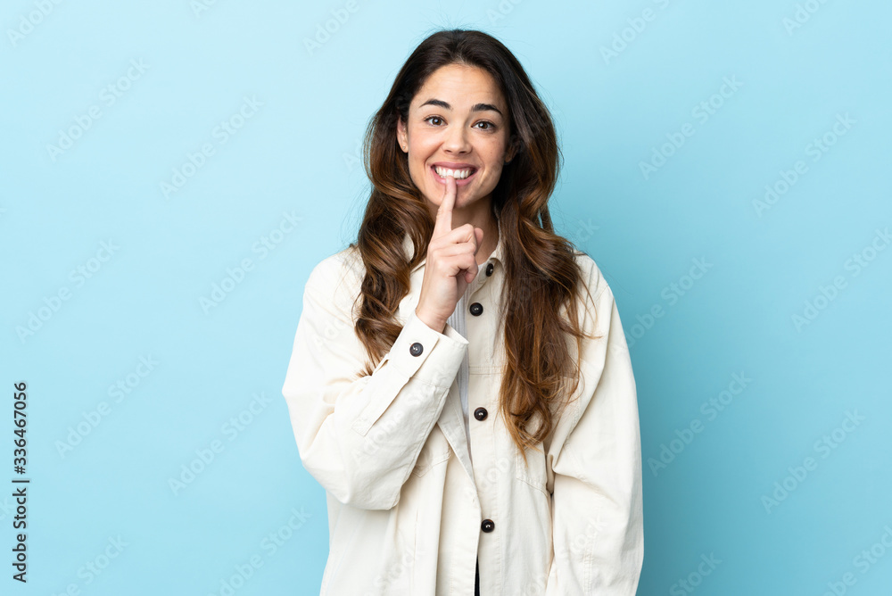 Woman over isolated background showing a sign of silence gesture putting finger in mouth Woman over isolated background showing a sign of silence gesture putting finger in mouth