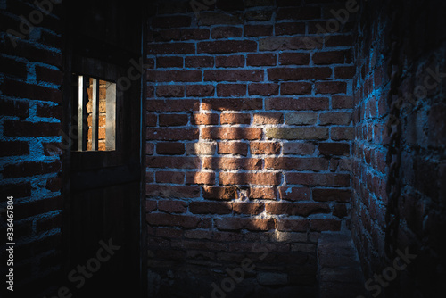 Light coming through a window on the brick wall in prison. Hight contrast dark shot