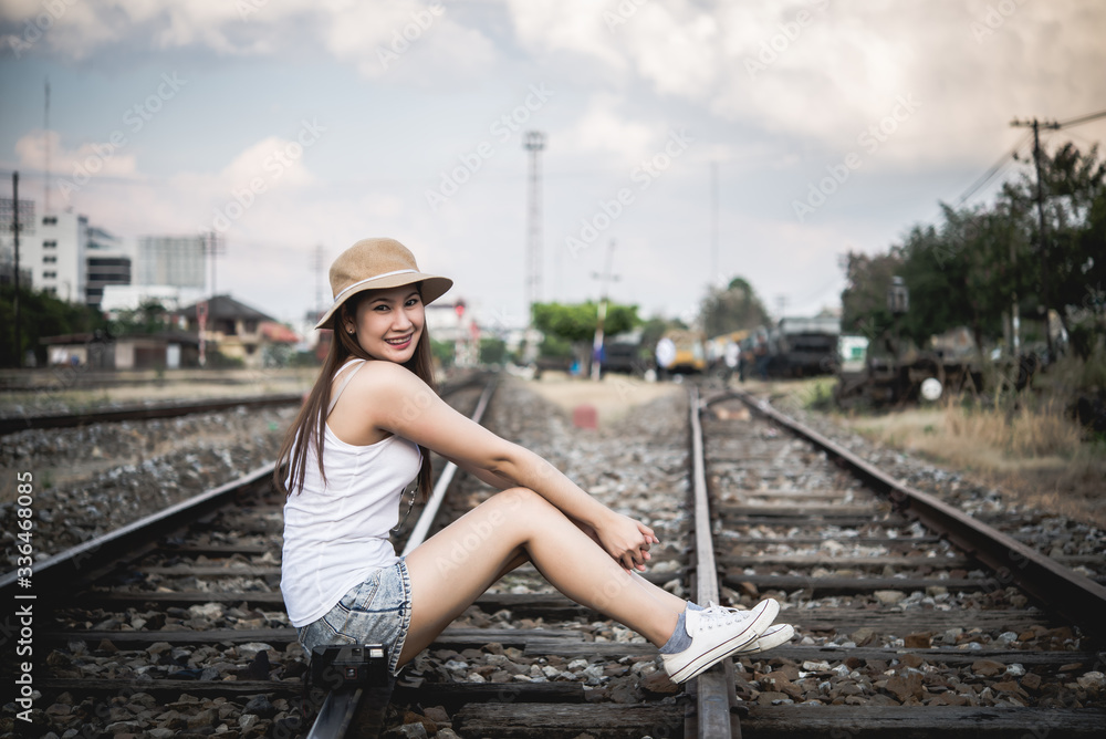 Portrait of beautiful asian woman  in A white T-shirt with camera in hand on the railway vintage style,Thailand people
