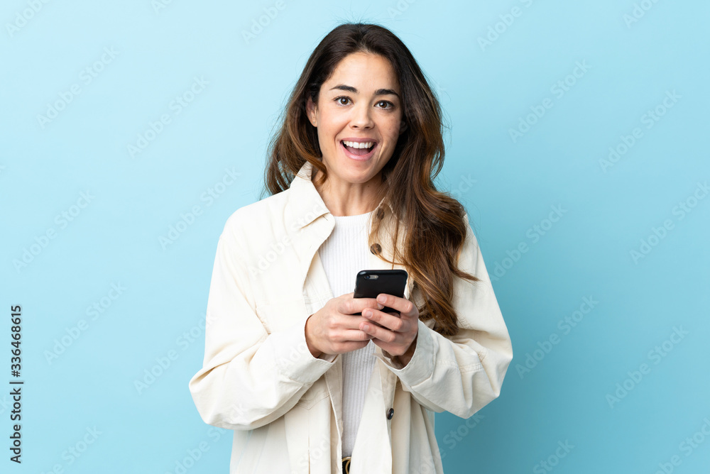 Woman over isolated background surprised and sending a message