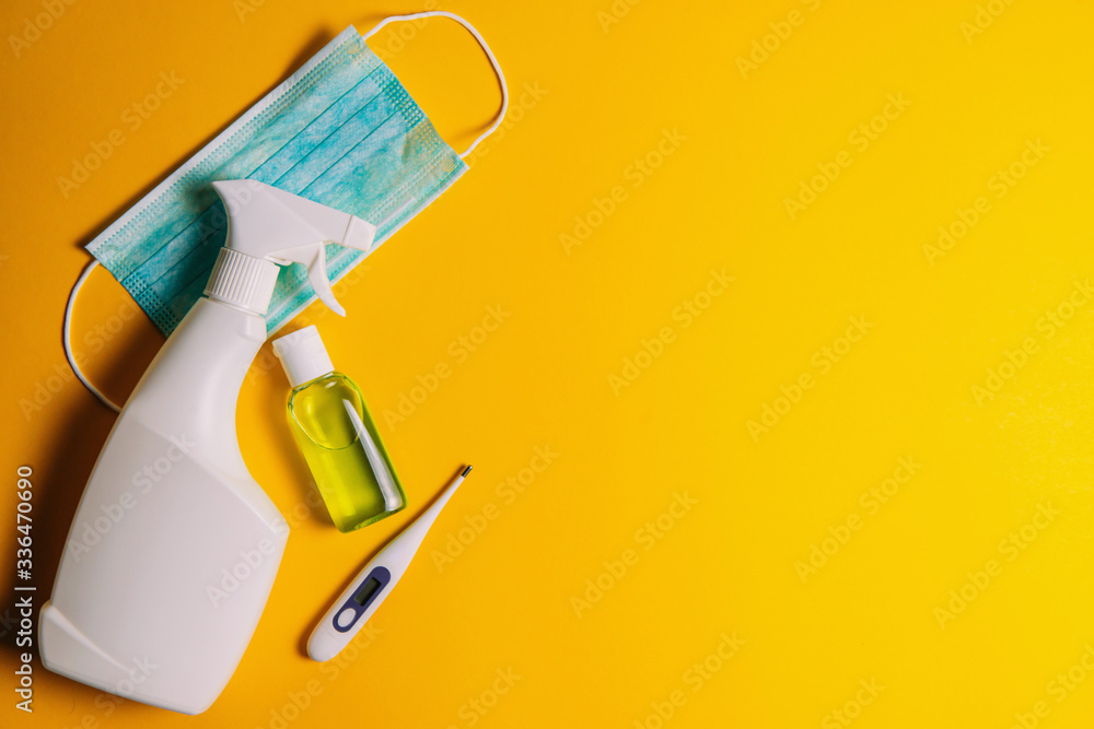 Medical face protection mask, alcohol antiseptic, disinfectant liquid, thermometer on a yellow background with place for text, the concept of the fight against coronavirus Medical face protection mask, alcohol antiseptic, disinfectant liquid, thermometer on a yellow background with place for text, the concept of the fight against coronavirus