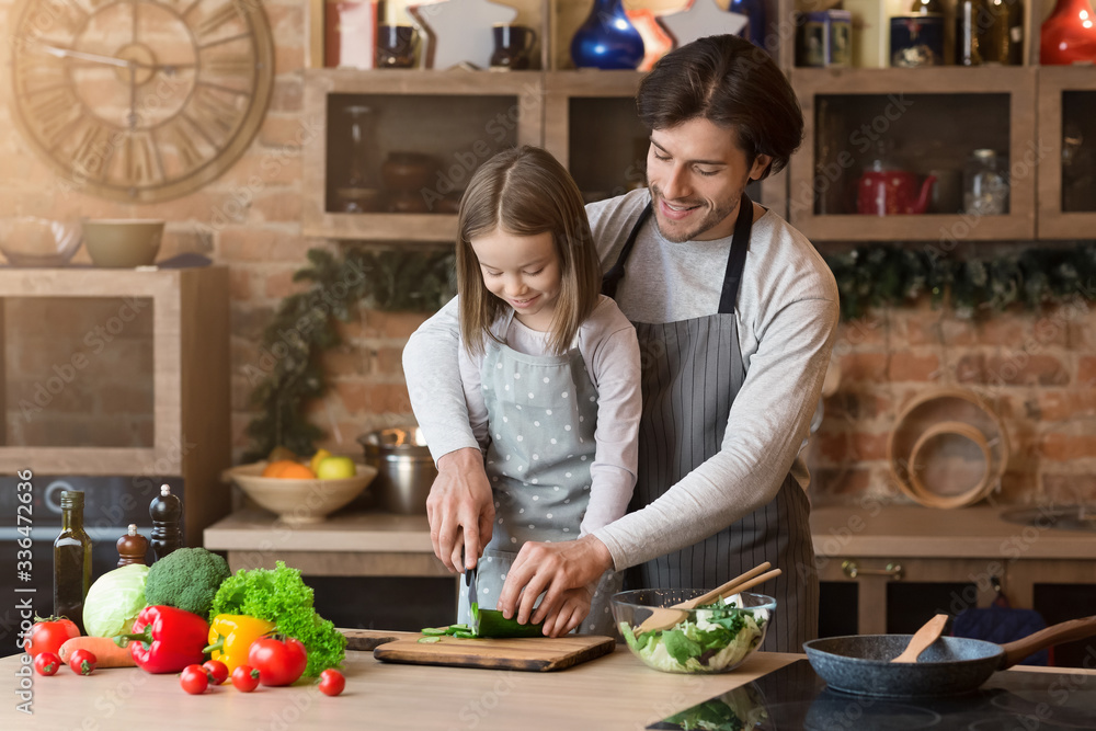 Caring father teaching his adorable daughter how to cook healthy food