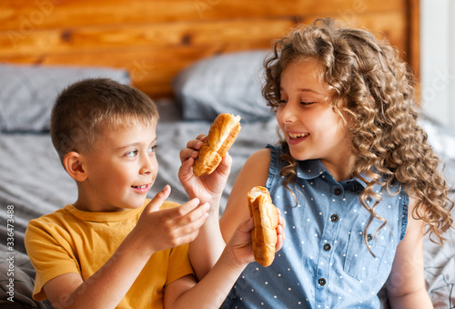 two children brother and sister eat buns in the bedroom room photo
