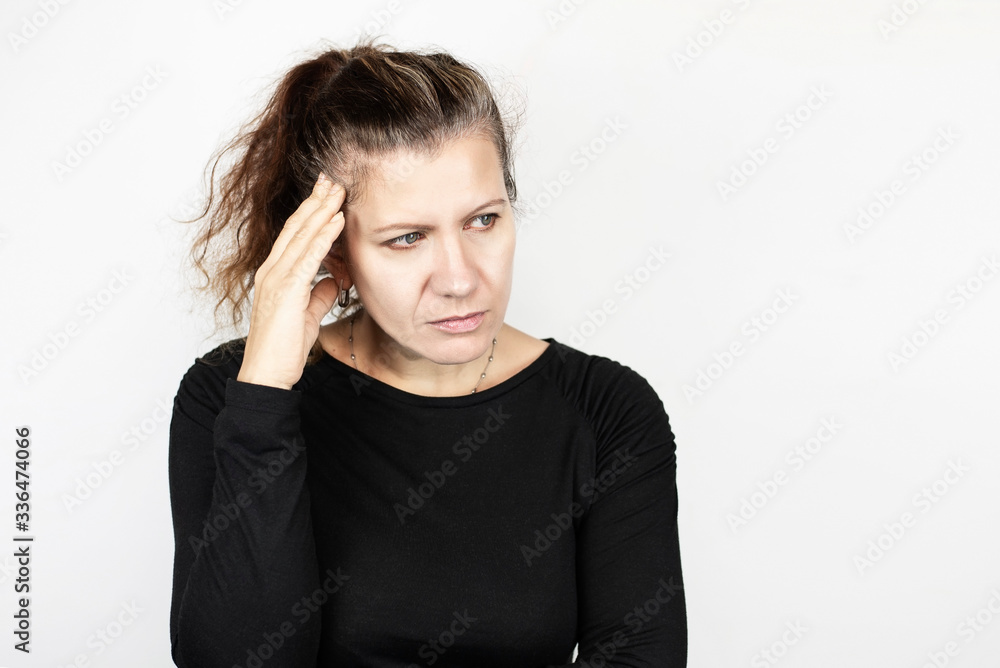 Middle-aged woman holding her head and looking away on a light background, a sad woman because her head is sore, her hair is turning gray Middle-aged woman holding her head and looking away on a light background, a sad woman because her head is sore, her hair is turning gray