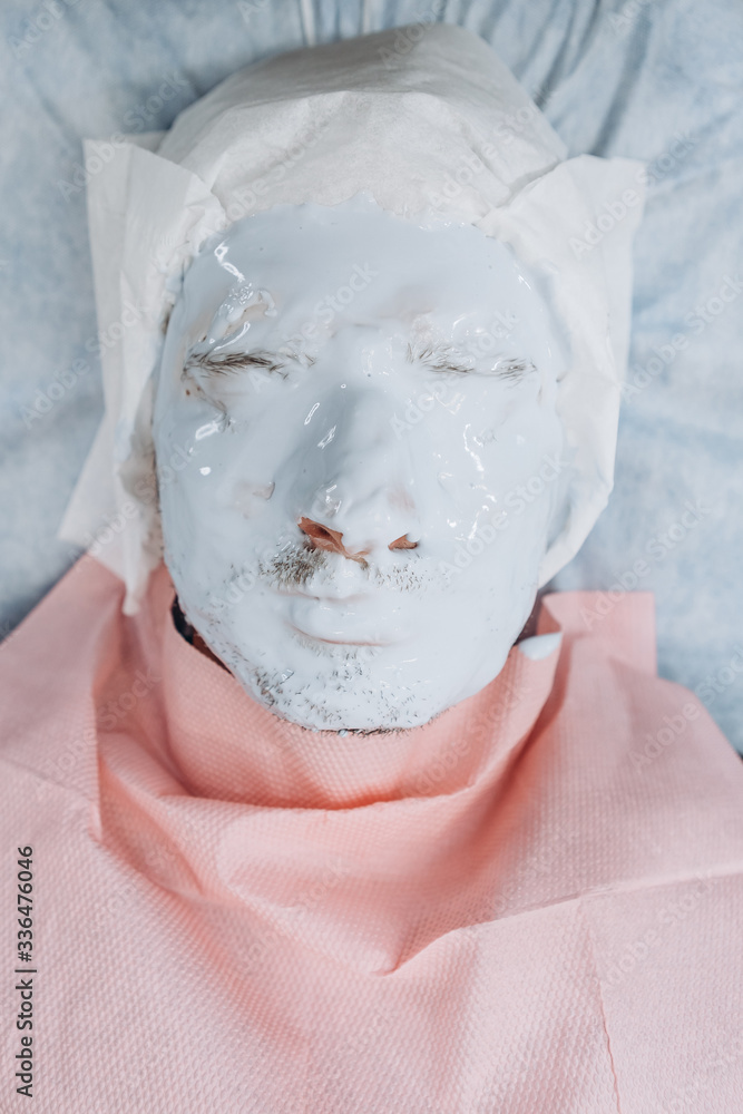 Spa facial skin care for men, applying removal of blue charcoal mask from nose face in spa salon