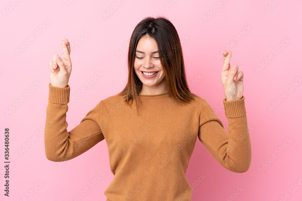 Young woman over isolated pink background with fingers crossing Young woman over isolated pink background with fingers crossing