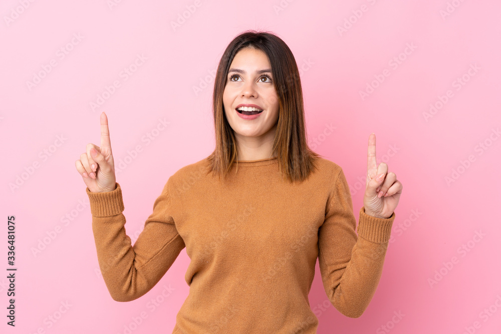 Young woman over isolated pink background surprised and pointing up Young woman over isolated pink background surprised and pointing up