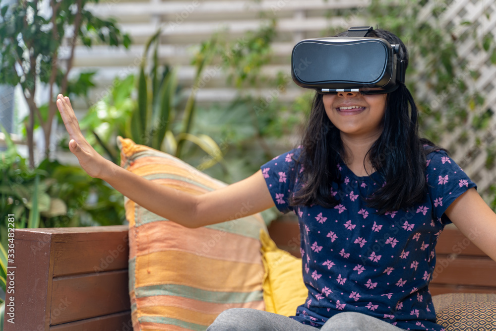 Fototapeta premium Indian Asian girl viewing through a Virtual Reality device, experiencing immersive technology