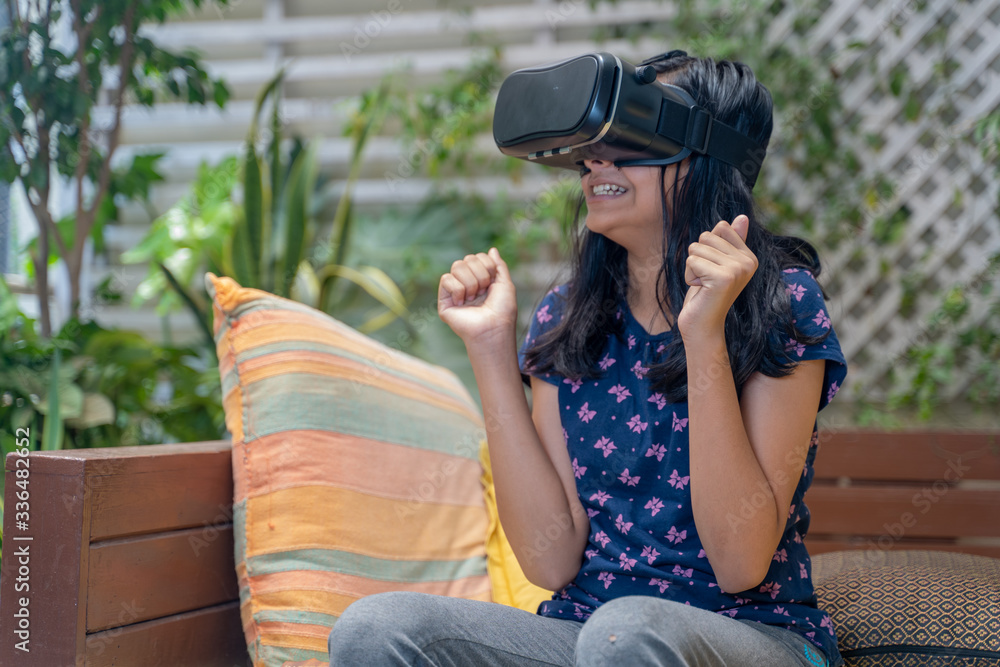 Fototapeta premium Indian Asian girl viewing through a Virtual Reality device, experiencing immersive technology