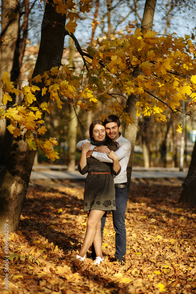 guy with a girl cuddling against a background of yellow foliage. Autumn in the park. sunny day