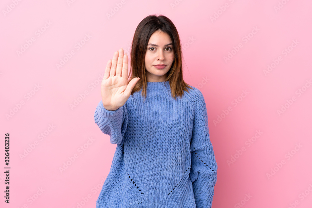 Young woman with blue sweater over isolated pink background making stop gesture with her hand - obrazy, fototapety, plakaty 