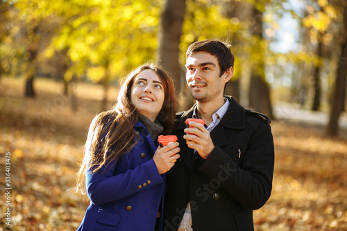 guy with a girl drink coffee in a park. Autumn in the park. sunny day