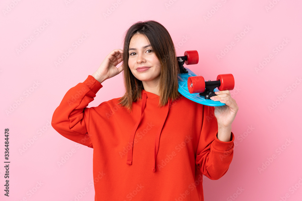 Young skater woman over isolated pink background Young skater woman over isolated pink background