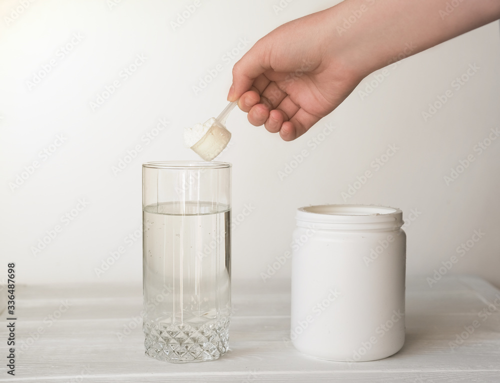 hand holding scoop of fish collagen. collagen peptides in container or jar.  glass of water for mixing drink. Healthcare supplement concept. collagen  powder for skin and joints . Photos | Adobe Stock