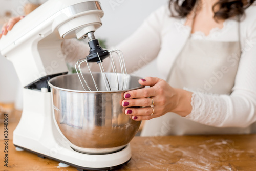 Close up of women's hands holding a large mixer
