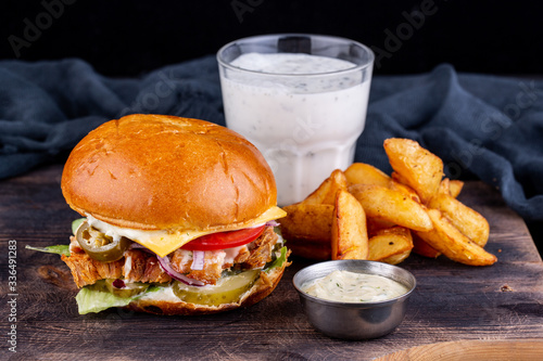 Pork hamburger with cheese, tomatoes and pickles, with sour ketchup, potatoes and a glass of kefir