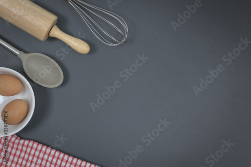 Wooden dough roller and whisk on the black table.