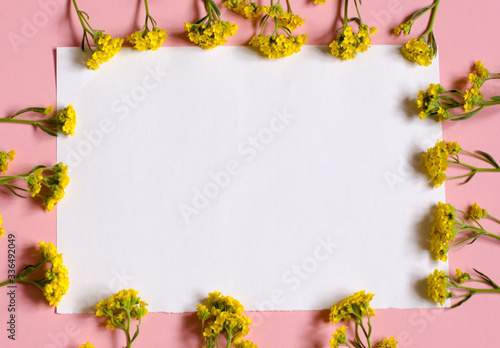 Fototapeta Naklejka Na Ścianę i Meble -  Frame of flowers. White piece of paper sheet on a pink background. Place for your text. Floral background.